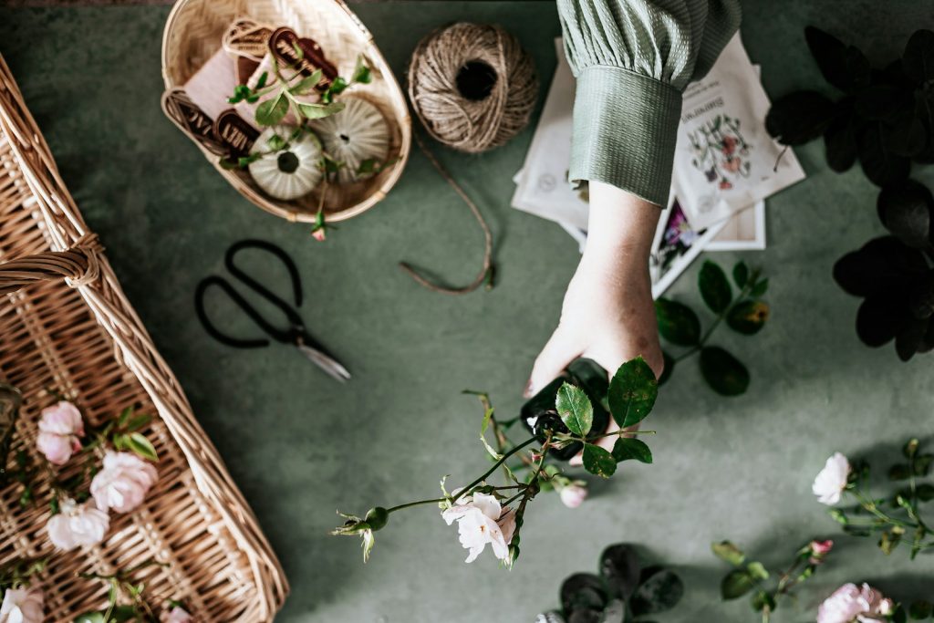 Flower arranging arm holds wild roses. twine, basket and scissors also pictured